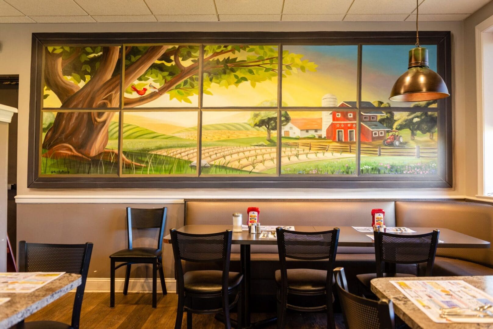 A restaurant with tables and chairs in front of a painting.