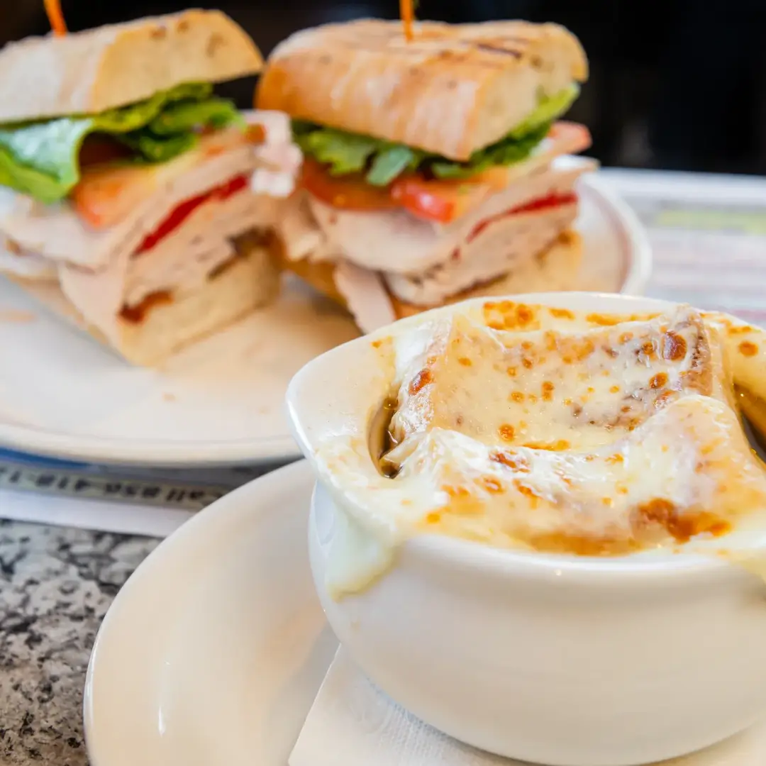 A plate with two sandwiches and a bowl of soup.